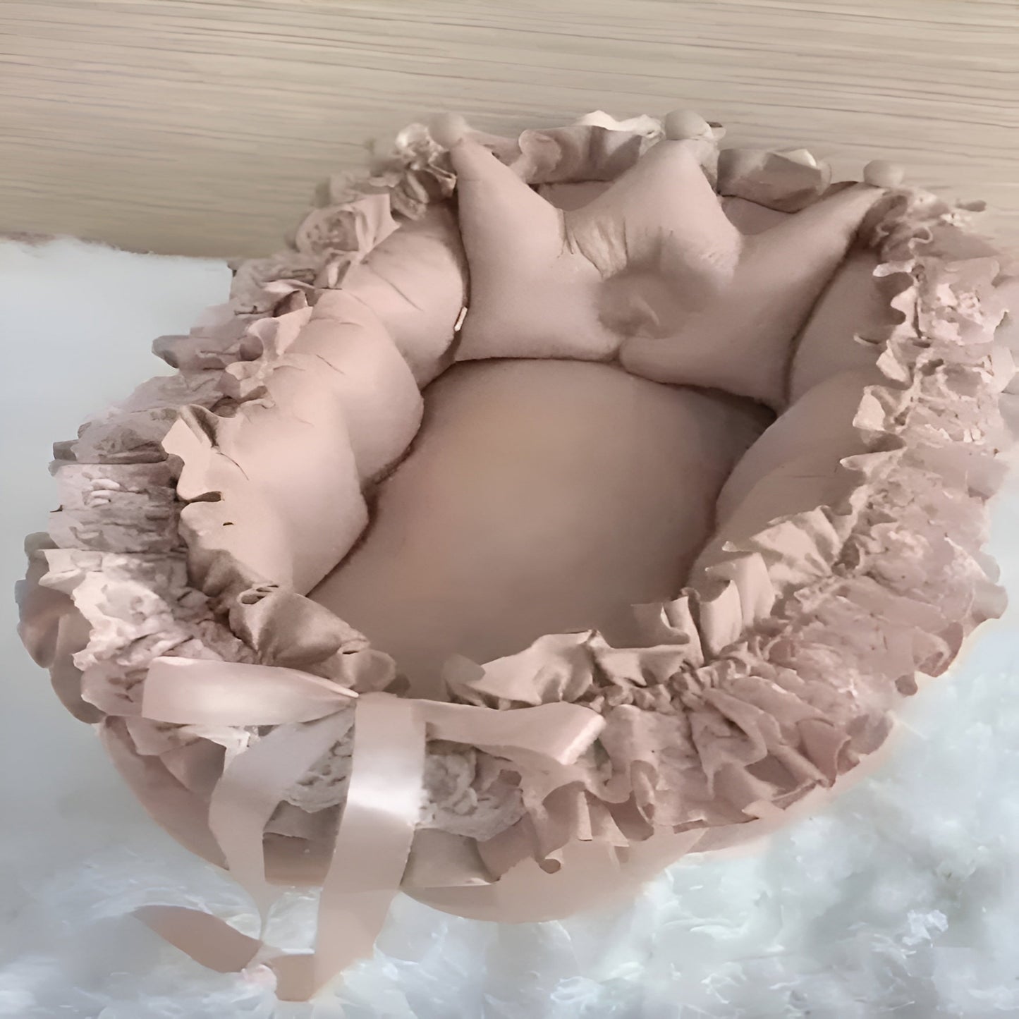 Pink baby crib with ruffled details on a white background