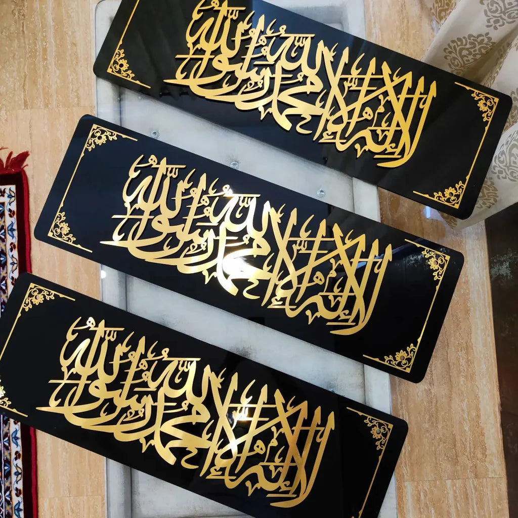 Three black rectangular signs with gold Arabic calligraphy on a wooden surface.