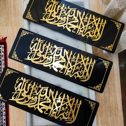 Three black rectangular signs with gold Arabic calligraphy on a wooden surface.