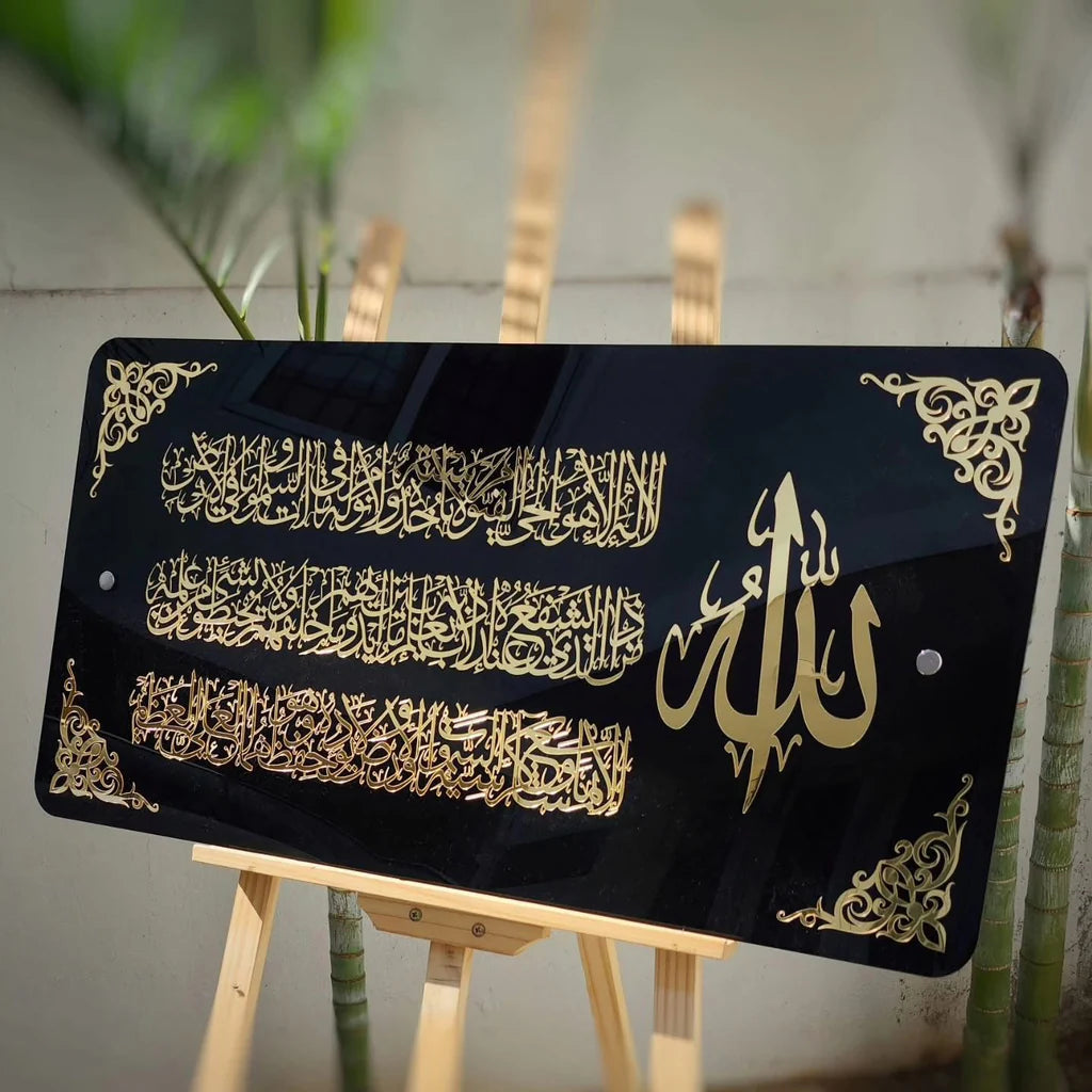 Decorative black board with gold Arabic calligraphy on a wooden stand.