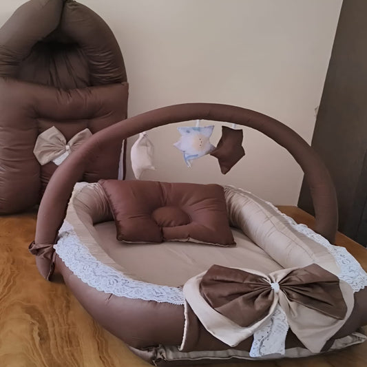 Brown baby bassinet with decorative bows and lace on a wooden floor.