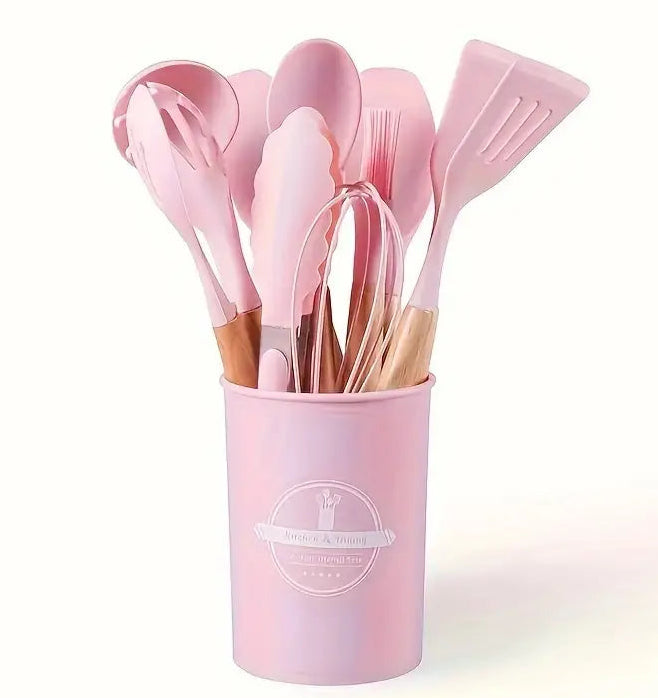 Set of pink kitchen utensils in a holder on a white background