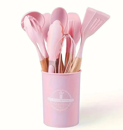 Set of pink kitchen utensils in a holder on a white background