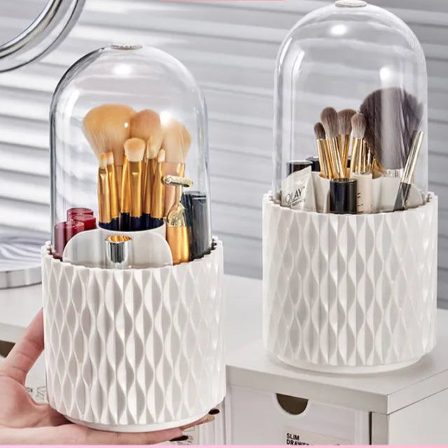 White cosmetic holders with makeup brushes and products under a glass dome, branded 'Pinky Beauty'.
