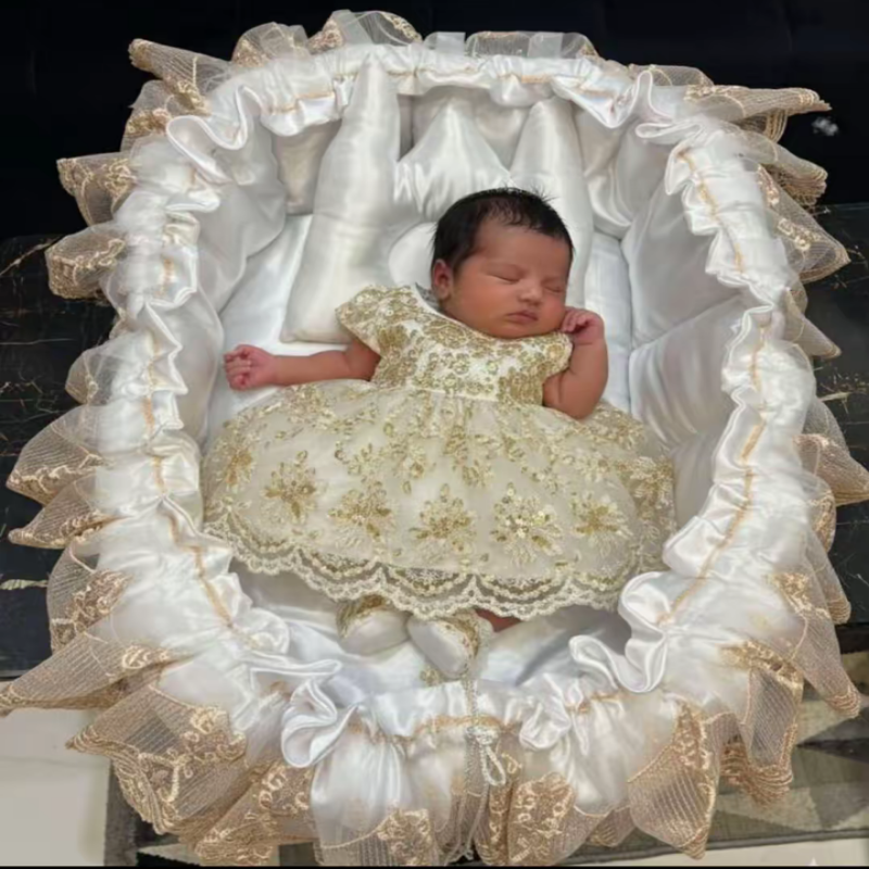 Newborn baby in a decorative crib with ruffled edges